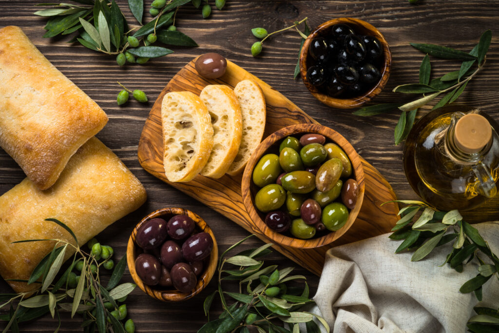 Olives, olive oil and ciabatta on wooden table
